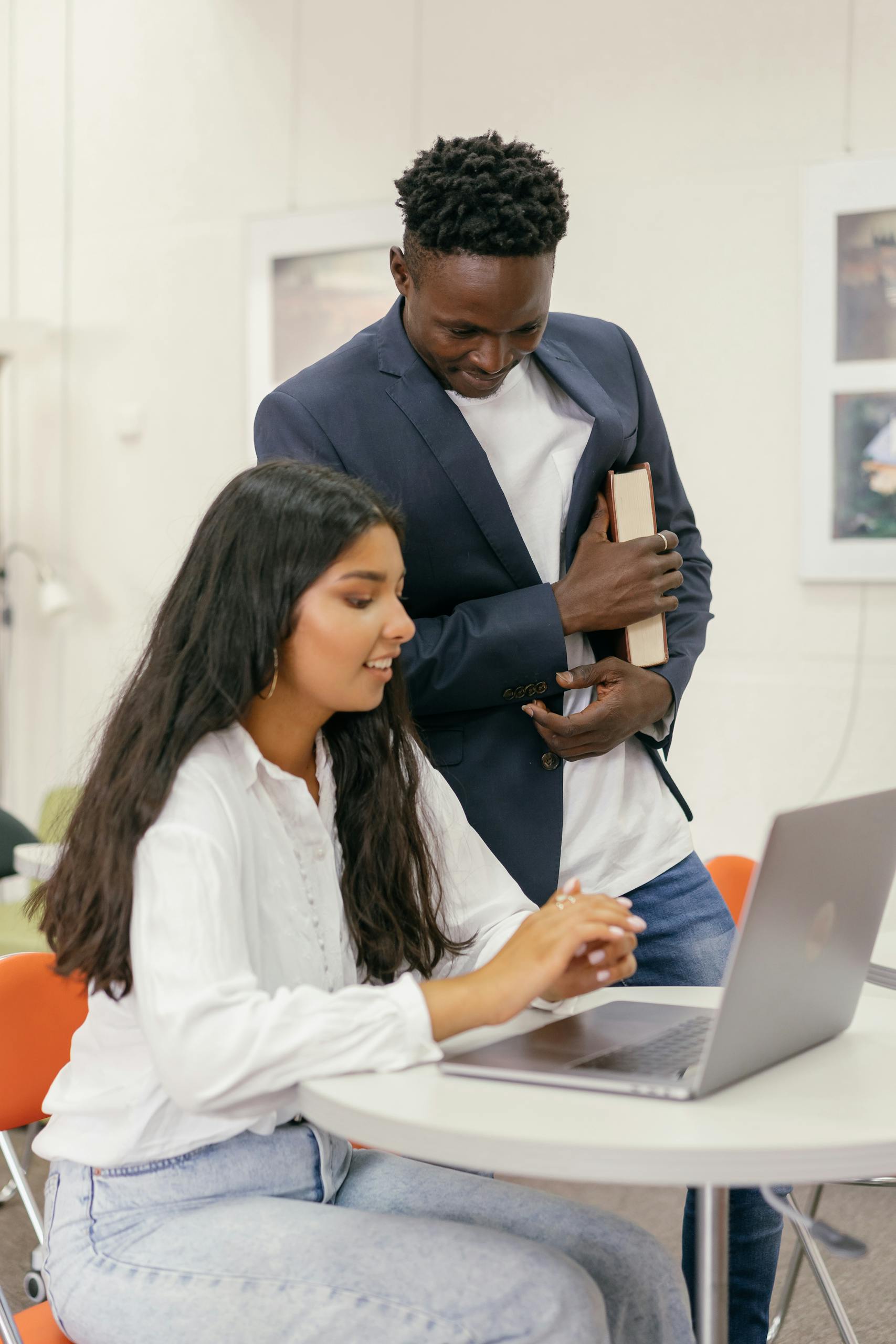 Two students working together on a laptop indoors at college.